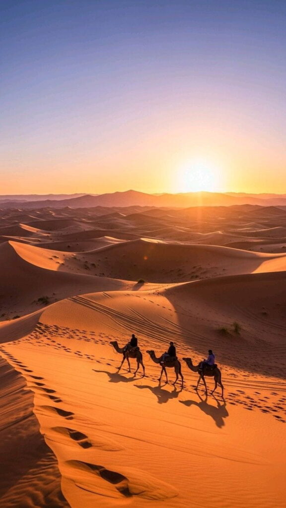Camel caravan crossing golden dunes at sunrise during a private Sahara Desert tour from Tangier to Merzouga.