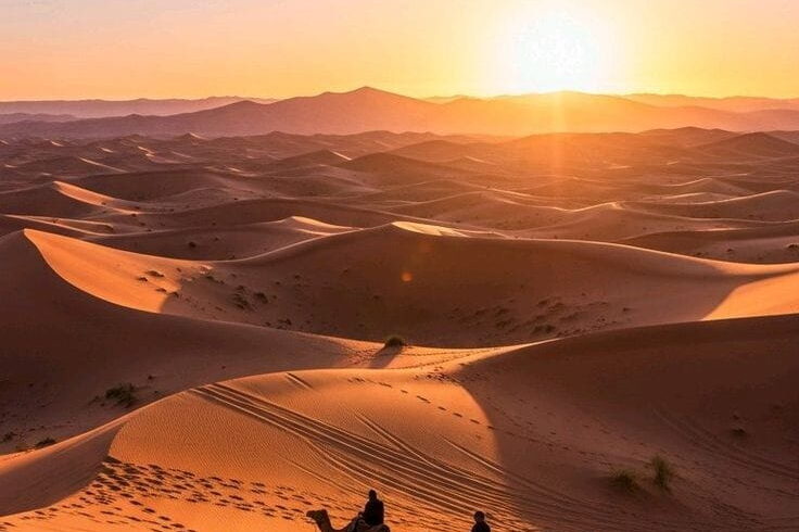 Camel caravan crossing golden dunes at sunrise during a private Sahara Desert tour from Tangier to Merzouga.