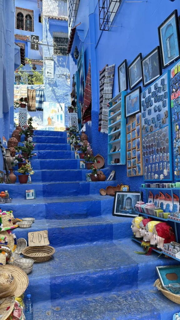 Blue painted steps in Chefchaouen filled with handmade souvenirs and local crafts during a Morocco cultural tour.