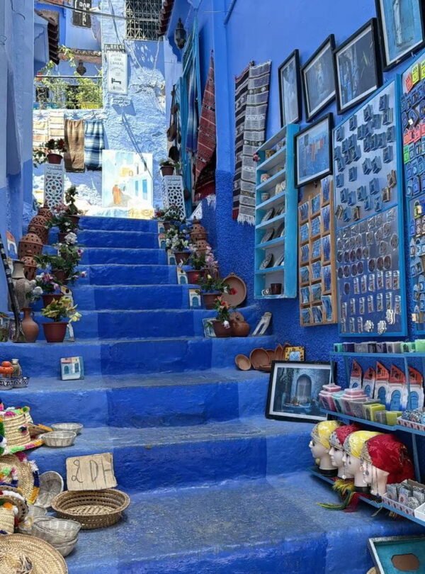 Blue painted steps in Chefchaouen filled with handmade souvenirs and local crafts during a Morocco cultural tour.