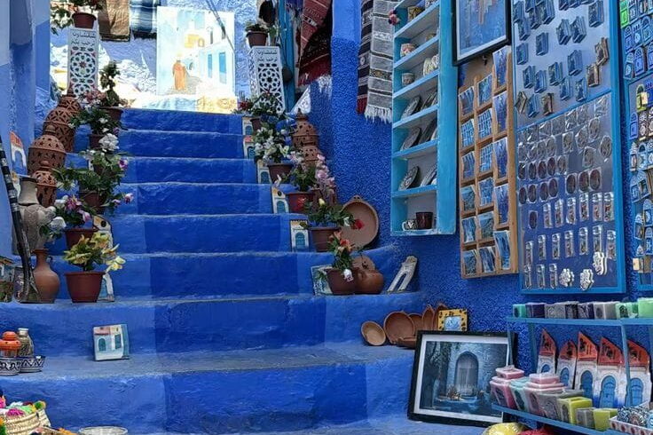 Blue painted steps in Chefchaouen filled with handmade souvenirs and local crafts during a Morocco cultural tour.