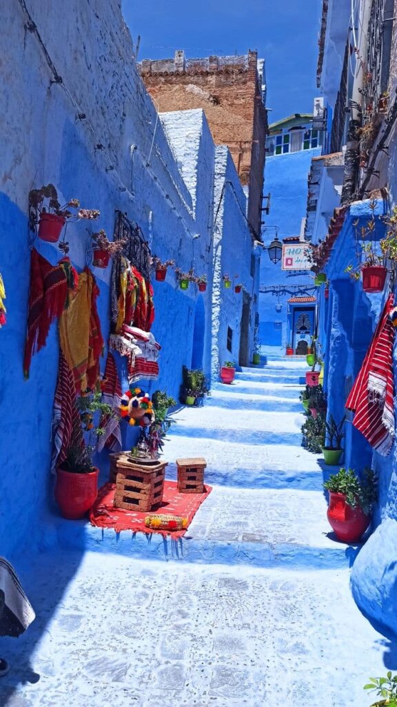 Quiet blue alley in Chefchaouen with colorful decorations and traditional houses during a guided Morocco tour.