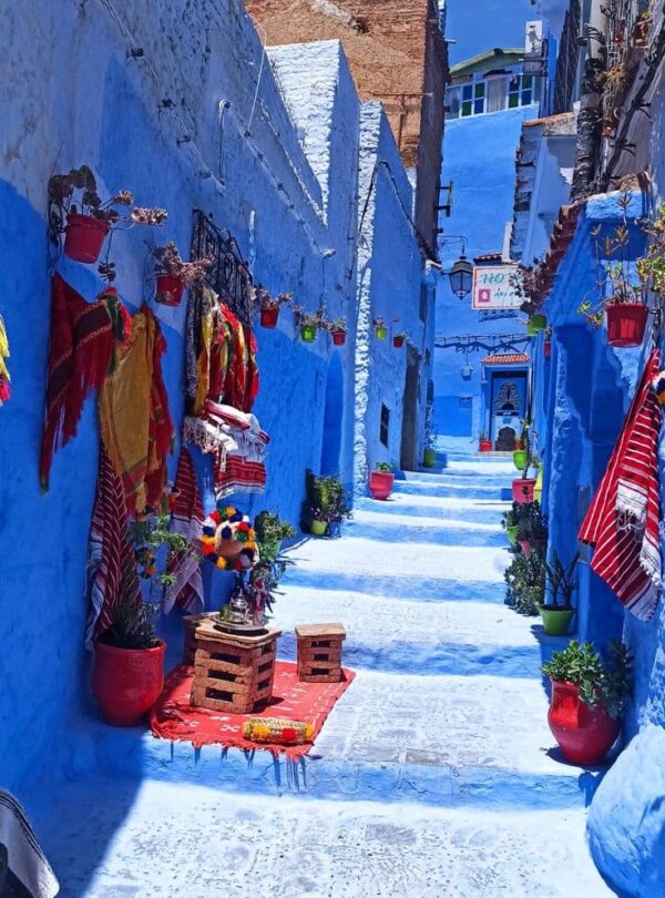Quiet blue alley in Chefchaouen with colorful decorations and traditional houses during a guided Morocco tour.