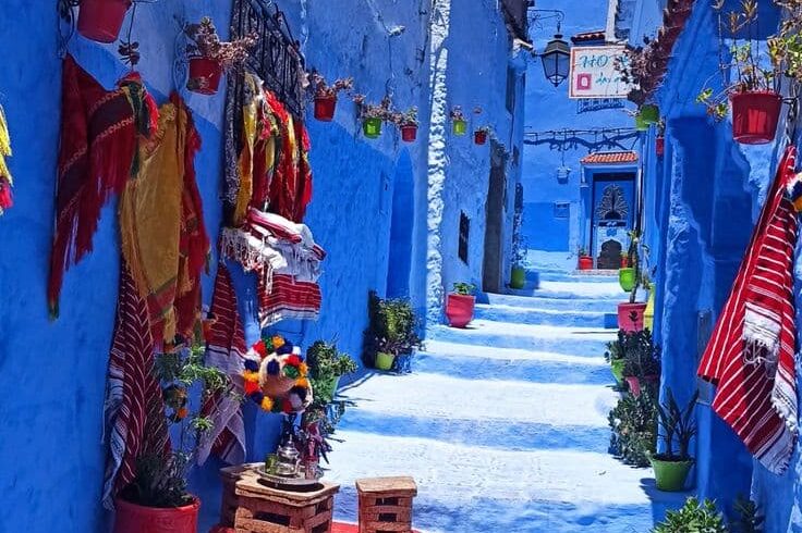 Quiet blue alley in Chefchaouen with colorful decorations and traditional houses during a guided Morocco tour.