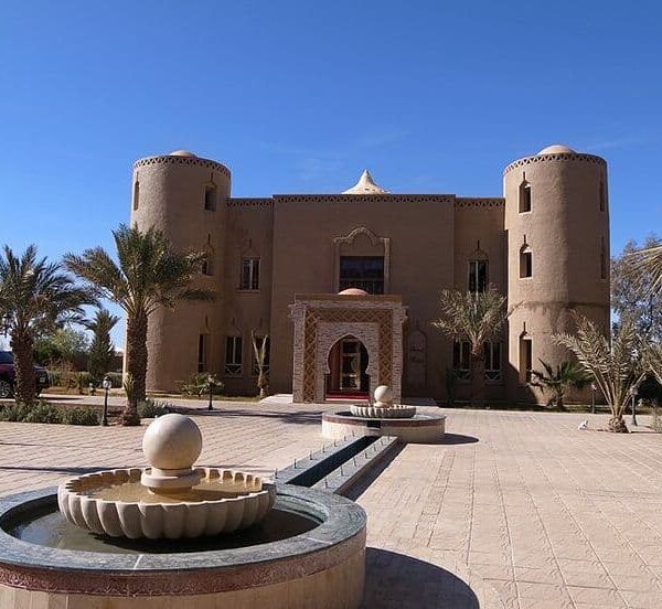 Traditional kasbah style desert hotel entrance in Erfoud Sahara Morocco with palm trees and fountain