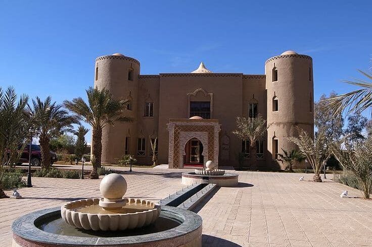 Traditional kasbah style desert hotel entrance in Erfoud Sahara Morocco with palm trees and fountain