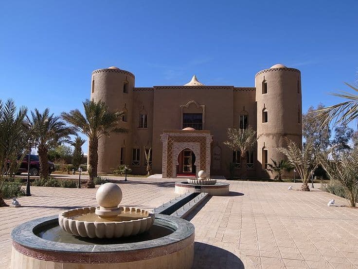 Traditional kasbah style desert hotel entrance in Erfoud Sahara Morocco with palm trees and fountain