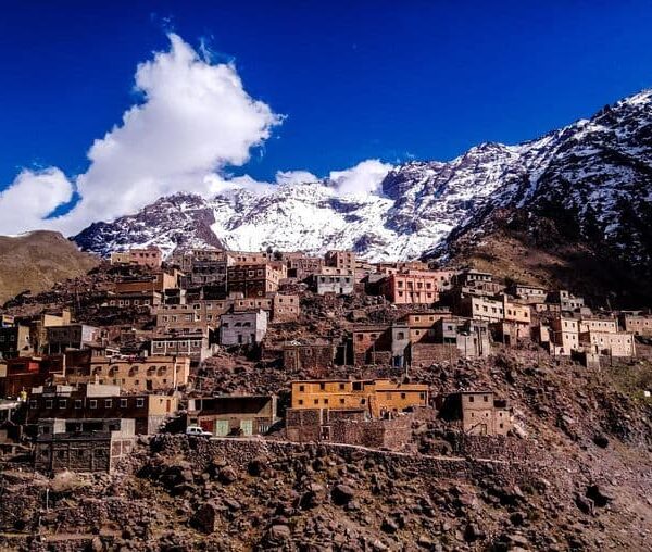 Traditional Berber houses in Imlil village surrounded by snow-capped High Atlas Mountains near Marrakech, Morocco.