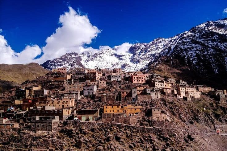 Traditional Berber houses in Imlil village surrounded by snow-capped High Atlas Mountains near Marrakech, Morocco.