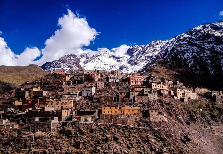 Traditional Berber houses in Imlil village surrounded by snow-capped High Atlas Mountains near Marrakech, Morocco.