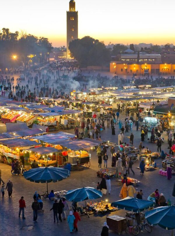 Busy evening atmosphere at Jemaa el-Fna square in Marrakech with food stalls and local performers.