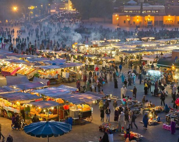 Busy evening atmosphere at Jemaa el-Fna square in Marrakech with food stalls and local performers.