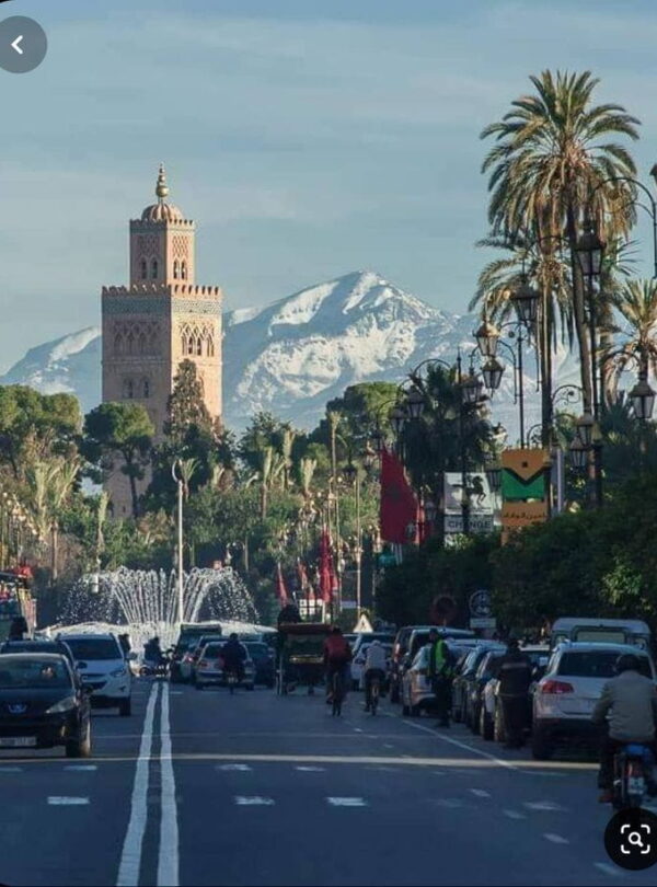 Street view near Koutoubia Mosque in Marrakech with palm trees and local life, capturing the energy of the Red City.