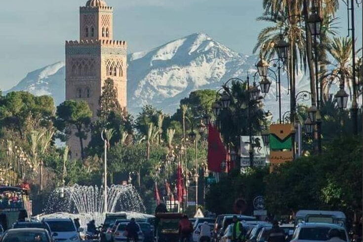Street view near Koutoubia Mosque in Marrakech with palm trees and local life, capturing the energy of the Red City.