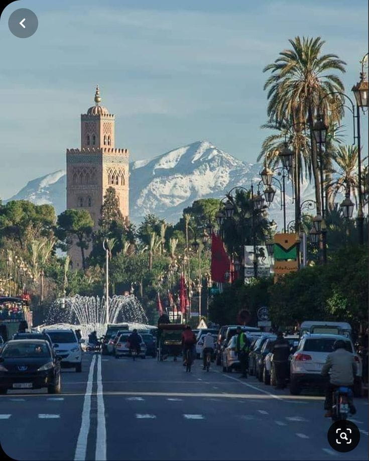 Street view near Koutoubia Mosque in Marrakech with palm trees and local life, capturing the energy of the Red City.