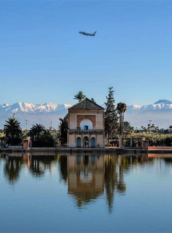Menara Gardens pavilion reflecting in water with Atlas Mountains in the background, a peaceful stop during a Marrakech cultural visit.