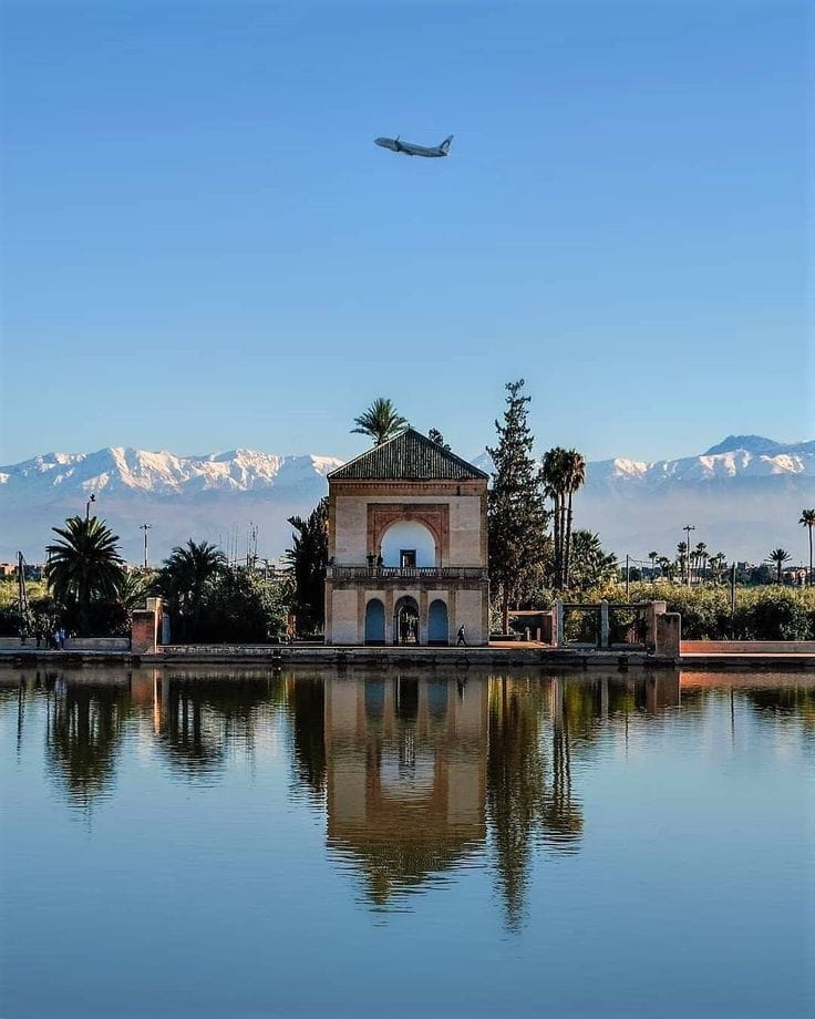 Menara Gardens pavilion reflecting in water with Atlas Mountains in the background, a peaceful stop during a Marrakech cultural visit.