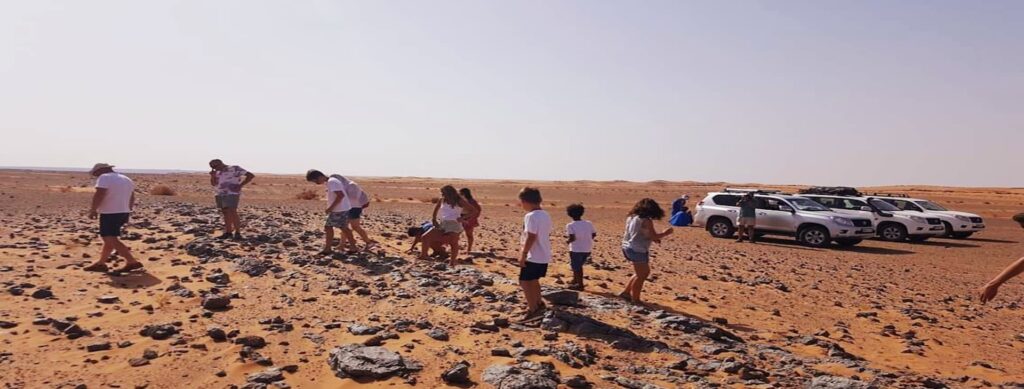 Travelers exploring fossil site during 4x4 desert excursion near Merzouga Sahara Morocco
