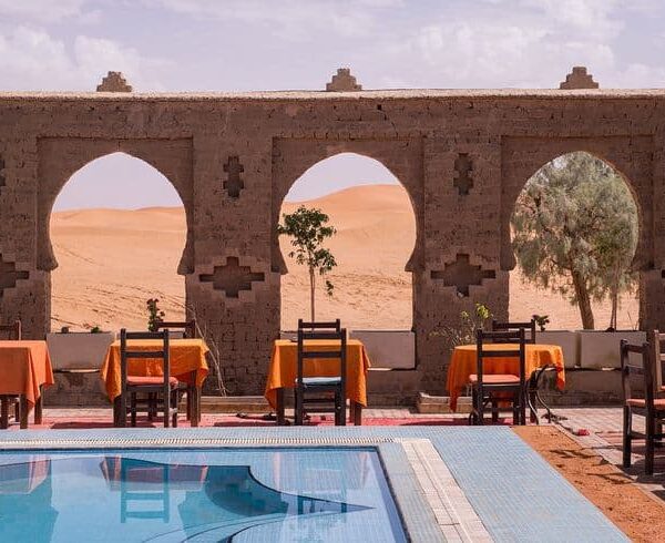 Desert auberge restaurant terrace with swimming pool overlooking sand dunes in Merzouga Sahara Morocco