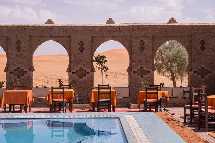 Desert auberge restaurant terrace with swimming pool overlooking sand dunes in Merzouga Sahara Morocco