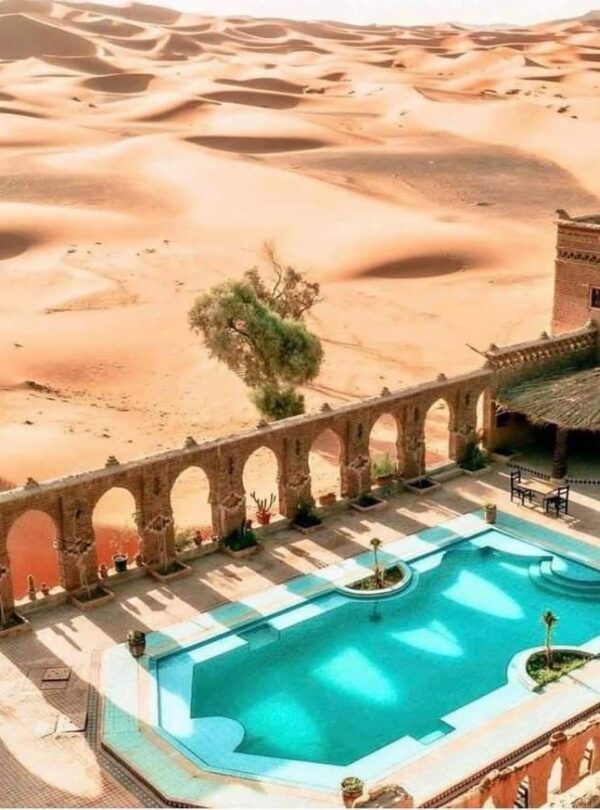 Desert hotel swimming pool overlooking Erg Chebbi dunes in Merzouga Sahara Morocco