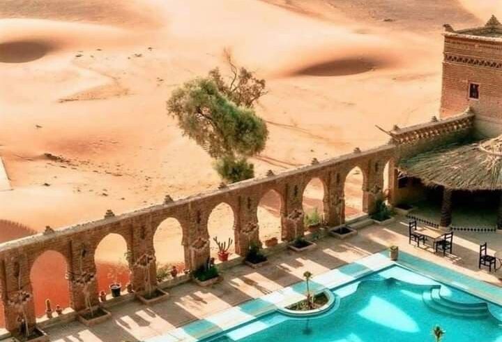 Desert hotel swimming pool overlooking Erg Chebbi dunes in Merzouga Sahara Morocco