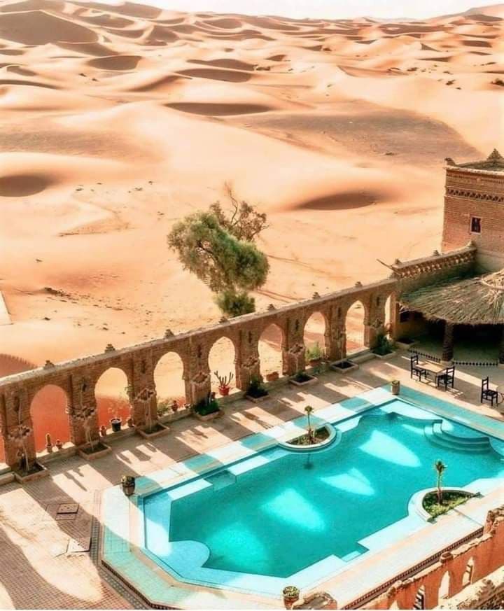 Desert hotel swimming pool overlooking Erg Chebbi dunes in Merzouga Sahara Morocco