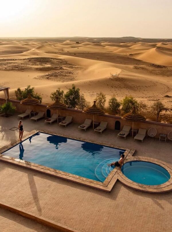Luxury desert hotel swimming pool overlooking Erg Chebbi sand dunes in Merzouga Morocco