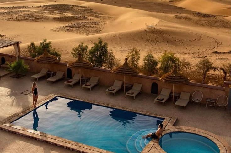 Luxury desert hotel swimming pool overlooking Erg Chebbi sand dunes in Merzouga Morocco
