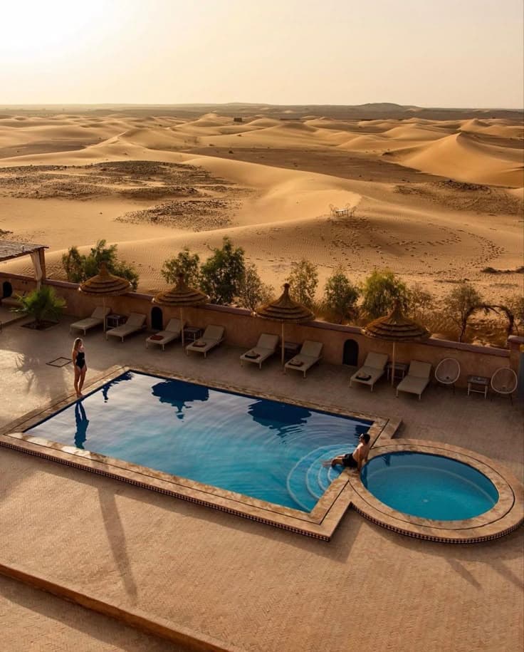 Luxury desert hotel swimming pool overlooking Erg Chebbi sand dunes in Merzouga Morocco