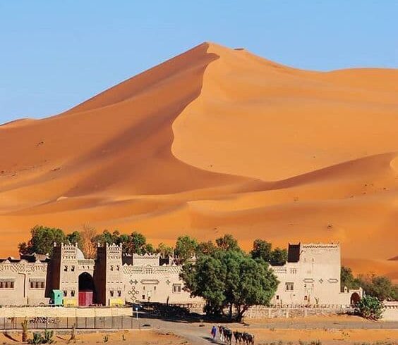 Traditional kasbah near towering Erg Chebbi sand dunes in Merzouga Sahara desert Morocco