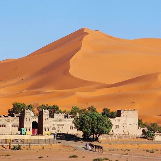 Traditional kasbah near towering Erg Chebbi sand dunes in Merzouga Sahara desert Morocco