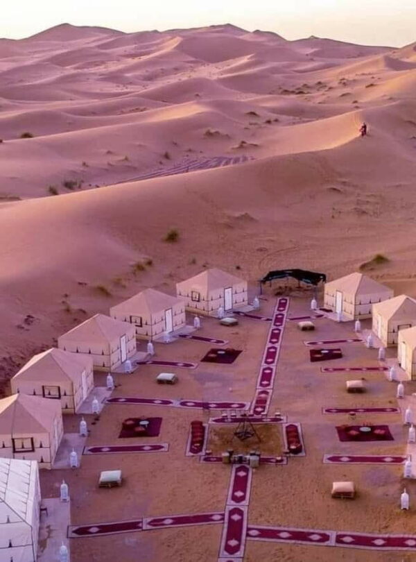 Luxury Sahara desert camp in Merzouga surrounded by golden dunes, a highlight of overnight experiences in southern Morocco.