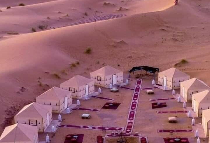 Luxury Sahara desert camp in Merzouga surrounded by golden dunes, a highlight of overnight experiences in southern Morocco.