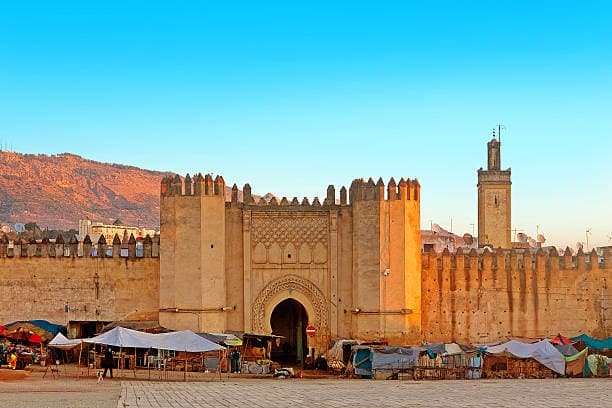 Historic gate and ancient walls of Fes Medina with local market stalls Morocco